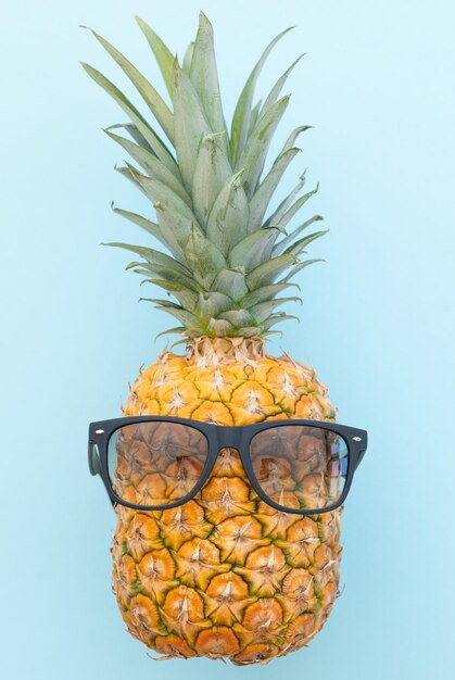 Ananas hipster avec lunettes de soleil sur fond bleu