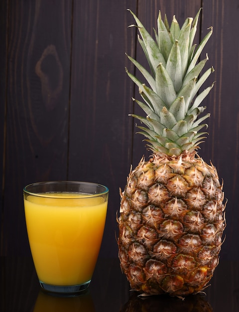 Ananas et jus dans un verre sur une surface sombre