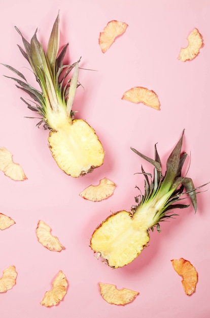 Ananas juteux mûr sur fond rose et quartiers d'ananas séchés autour