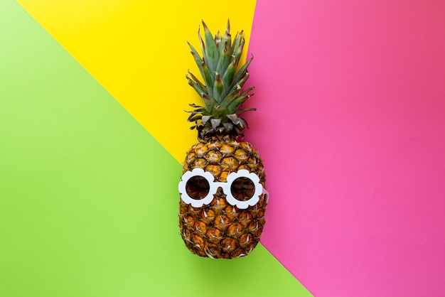 Ananas à lunettes de soleil blanches sur le fond coloré, Concept créatif de l'été