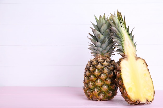 Ananas et moitié d'ananas sur une table en bois blanc