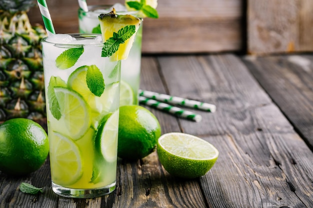 Ananas Mojito Sangria avec tranches de citron vert et menthe en verre sur fond de bois