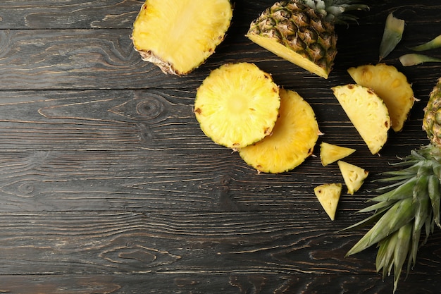 Ananas mûrs et tranches sur fond de bois, vue du dessus