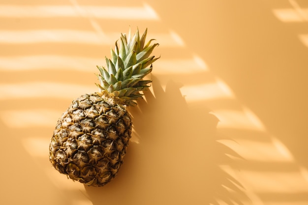 Photo ananas avec une ombre tendance dure sur fond jaune pastel.