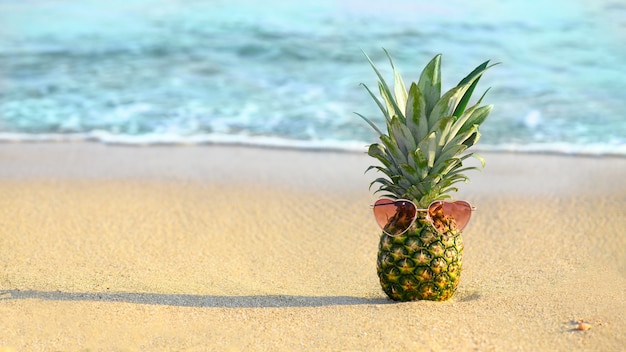 Ananas avec sanglasses forme chaleur sur la plage