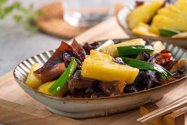 Ananas sauté avec champignon de l'oreille en bois noir. Nourriture délicieuse faite maison avec l'échalote sur le fond gris de table.