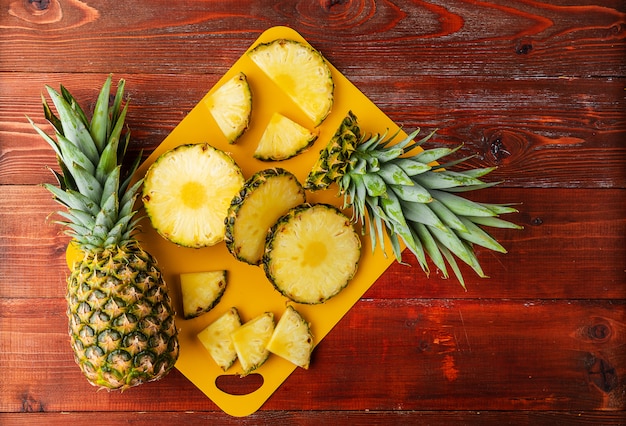 Ananas tropical mûr frais coupé en tranches sur un rackside jaune se trouvant sur une table en bois