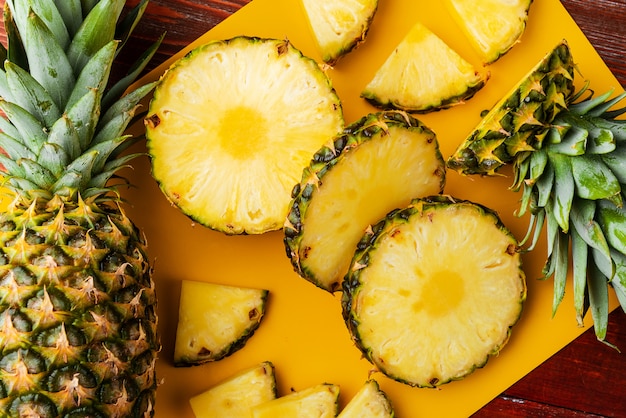 Ananas tropical mûr frais coupé en tranches sur un rackside jaune se trouvant sur une table en bois