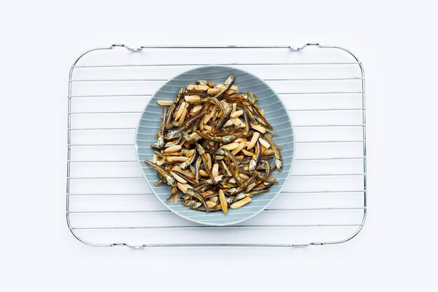 Anchois mélangés aux amandes en plaque sur fond blanc.