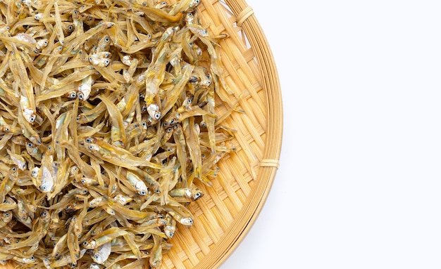 Anchois séchés dans un panier rond en bambou sur fond blanc