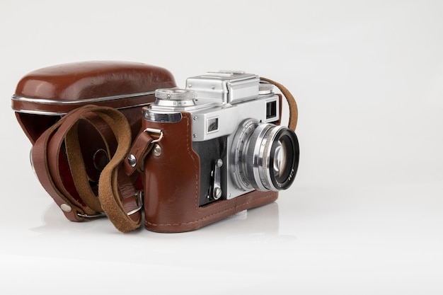 Ancien appareil photo argentique vintage en étui en cuir marron sur blanc isolé close up