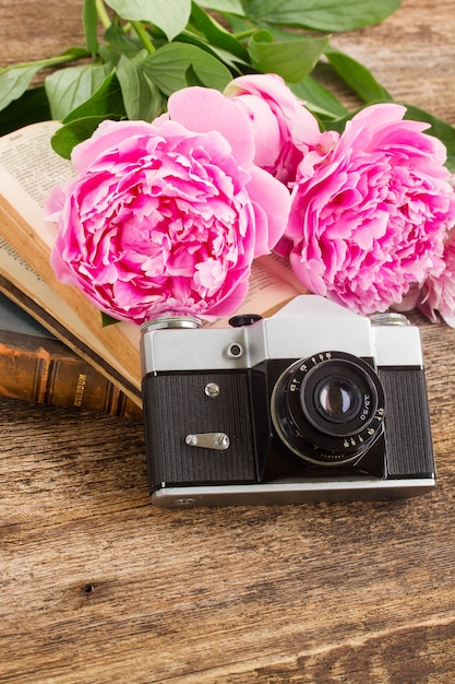 Ancien appareil photo avec des livres et des fleurs de pivoine fraîche