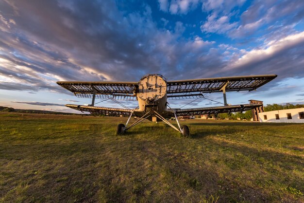 Ancien avion détruit sur le terrain dans les rayons du soleil couchant avec de beaux nuages