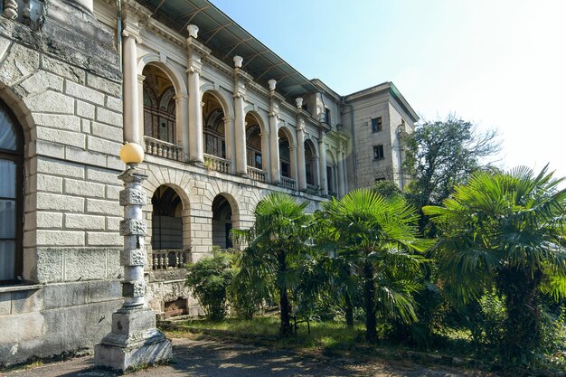 Ancien bâtiment en pierre grise avec colonnes et balcons et balustres dans un parc aux plantes tropicales