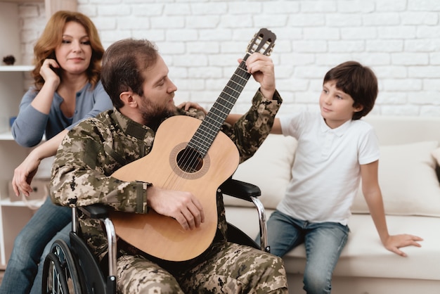 Un ancien combattant joue de la guitare Une femme et son fils écoutent sa musique