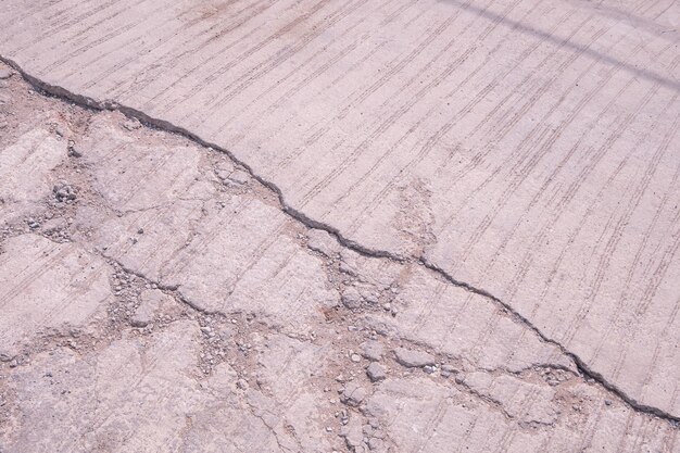L'ancien fond de route en béton endommagé avec une texture cassée et fissurée sur la surface