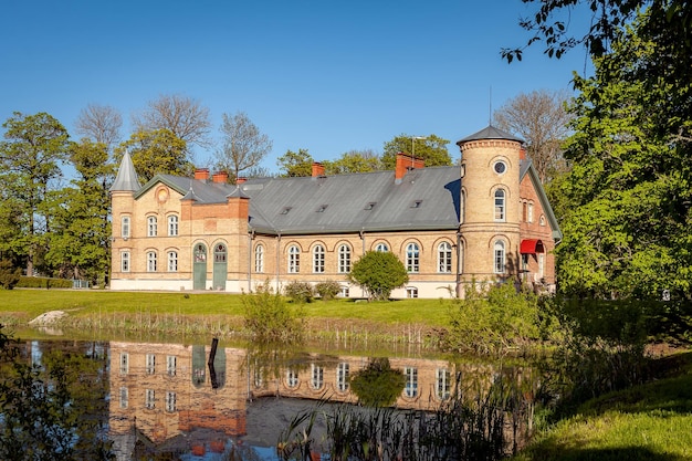 Photo ancien manoir en brique à lasila estonie paysage du domaine avec reflet dans l'étang