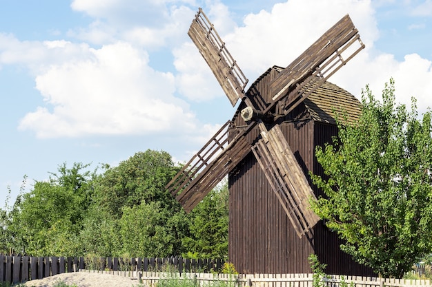 Ancien moulin à vent en bois au feuillage vert sous un ciel bleu avec des nuages à Vitachov, Ukraine. Parc national Horodyshche Novgorod-Svyatopolche. Monument historique