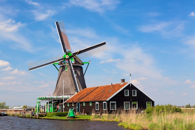 Ancien moulin à vent hollandais traditionnel avec maison ciel bleu dans le village de Zaanse Schans, Pays-Bas.