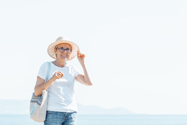 Ancien portrait en plein air senior avec espace de copie avec des lunettes lors d'une journée de voyage à la plage pendant l'exploration par temps froid. Nouvelles habitudes, lecture et mouvement pour une vie saine cette année d'entrée nouvelle vie.