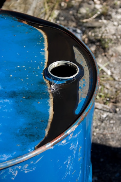 Photo ancien tambour à huile avec de l'huile noire sur le dessus qui a piégé une graine de pissenlit