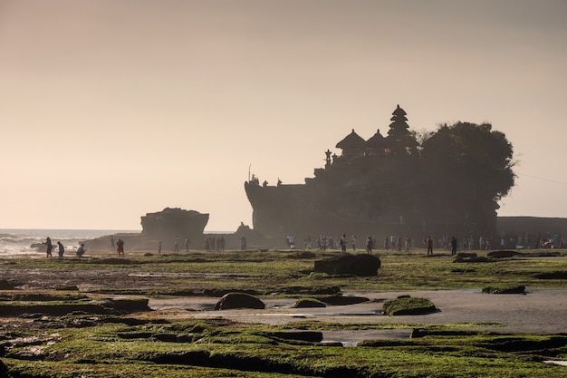 Ancien temple de Tanah Lot avec des touristes de rêve sur la côte