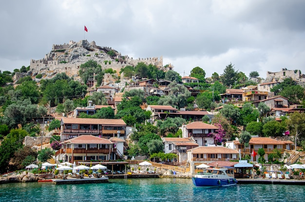 Ancien village de Simena avec château sur la montagne. Quai de bateau, beau paysage.