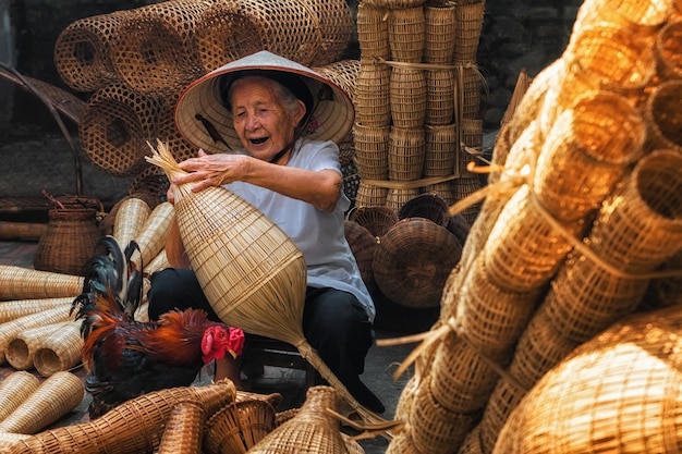 Ancienne artisan vietnamienne faisant le traditionnel piège à poissons en bambou