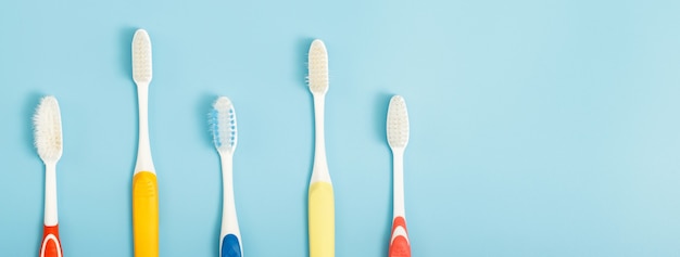 L'ancienne brosse à dents utilisée a expiré (endommagé) une variété de couleurs sur le fond bleu. concept Utilisé pour la fabrication de l'industrie de la santé Dentiste professionnel ou devrait souvent changer votre brosse à dents.