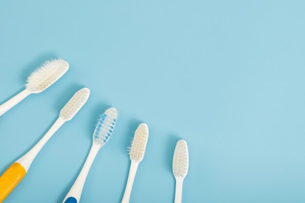 L'ancienne brosse à dents utilisée a expiré (endommagé) une variété de couleurs sur le fond bleu. concept Utilisé pour la fabrication de l'industrie de la santé Dentiste professionnel ou devrait souvent changer votre brosse à dents.