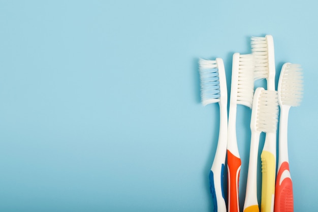 L'ancienne brosse à dents utilisée a expiré (endommagé) une variété de couleurs sur le fond bleu. concept Utilisé pour la fabrication de l'industrie de la santé Dentiste professionnel ou devrait souvent changer votre brosse à dents.
