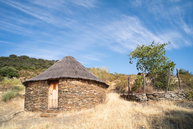 Ancienne cabane ou cabane de forme arrondie aux murs en pierre d'ardoise et au toit de genêts et de paille