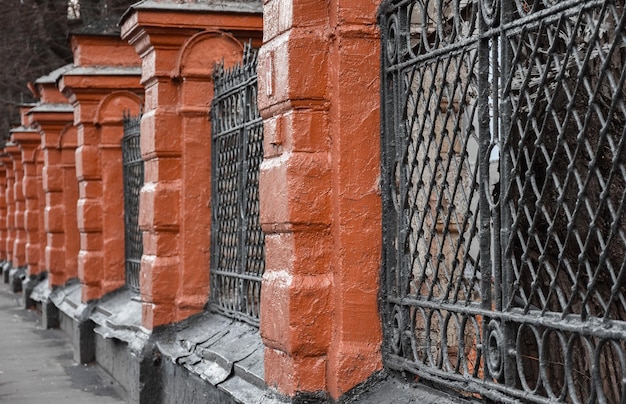 Ancienne clôture en brique rouge et clôture en treillis noir