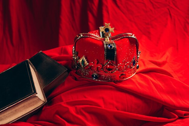 Ancienne couronne dorée avec des pierres précieuses sur un tissu rouge avec des livres