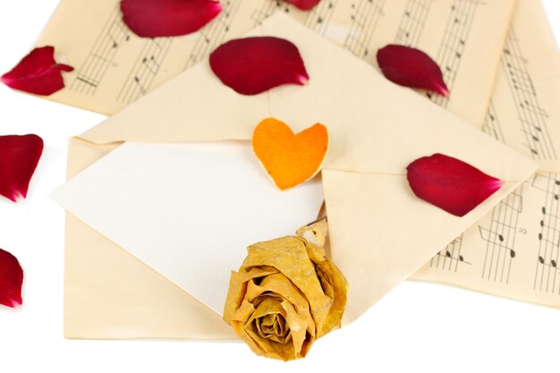 Ancienne enveloppe avec du papier vierge et rose séchée sur des feuilles de musique se bouchent