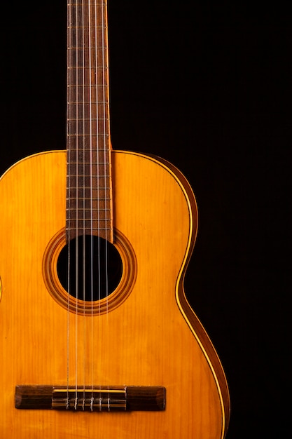 Ancienne guitare acoustique sur un mur noir.