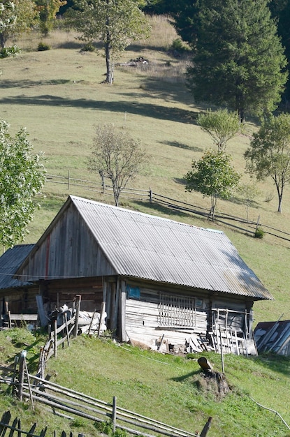 L&#39;ancienne hutte ukrainienne avec un toit en ardoise et une clôture en bois dans un champ verdoyant