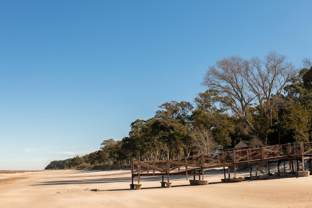 Ancienne jetée maintenant pont sur le sable de la plage de Kiyu avec les arbres sur les ravins de la côte