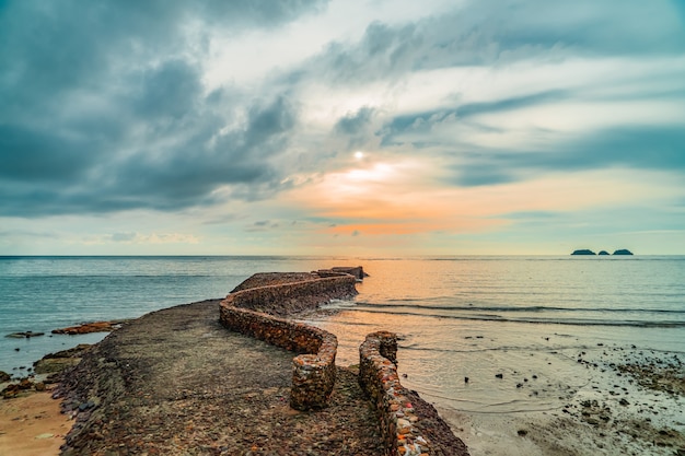 Ancienne jetée de roche de birck près de la côte au coucher du soleil.