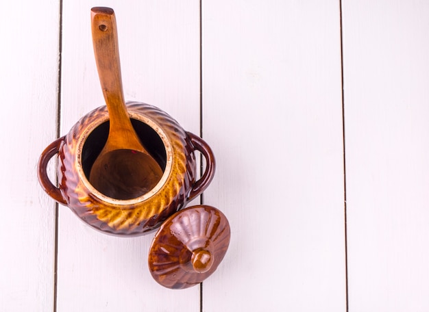 Ancienne mijoteuse cuisson et cuillère en bois sur table en bois blanc. Vue d'en-haut