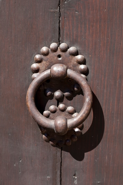 Ancienne poignée de porte italienne sur porte marron.