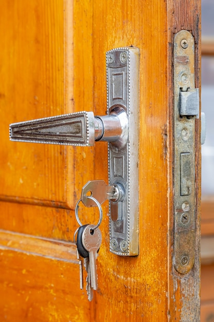 Ancienne poignée de porte avec serrure et porte-clés sur la porte ouverte en bois.