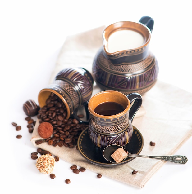 Ancienne poterie noire, grains de café, bonbons et une tasse de boisson