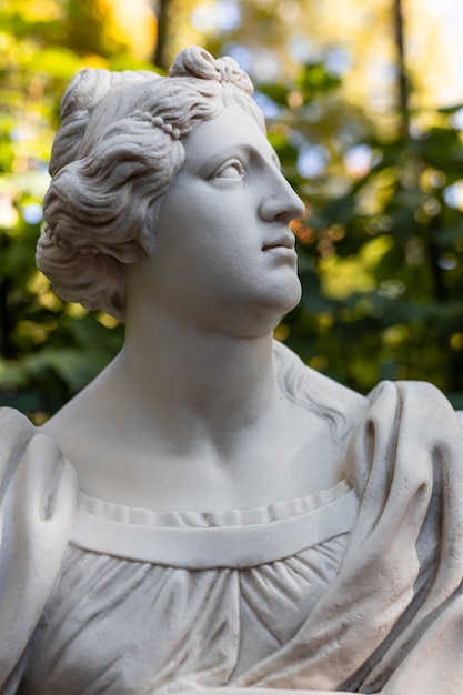 Ancienne statue de parc d'une femme sensuelle de l'époque de la Renaissance grecque ou italienne avec des fleurs dans le parc de la ville est allée aux couleurs dorées de l'automne,