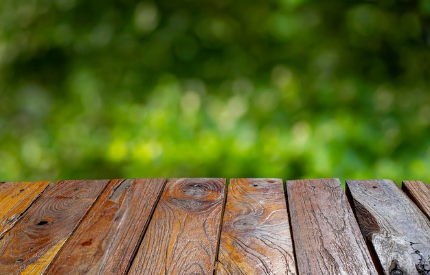 Ancienne table vide en bois de teck devant un fond de bokeh vert pour l'affichage du produit