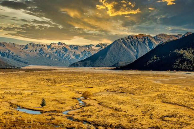 Ancienne vallée glaciaire enveloppée par la lumière du soleil de fin d'après-midi avec les magnifiques Alpes du Sud au loin