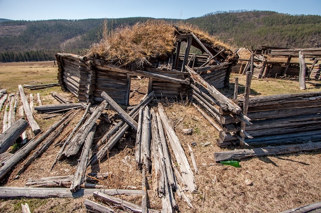 Ancienne yourte en ruine en bois. Fermer. Au premier plan des bûches pourries. Clôture pourrie.