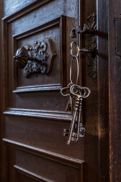 Anciennes clés dans un trou de serrure. Vieille porte en bois rouillée avec des clés.