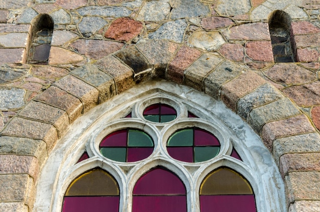 Anciennes fenêtres en verre cintrées installées dans un mur de château en pierre