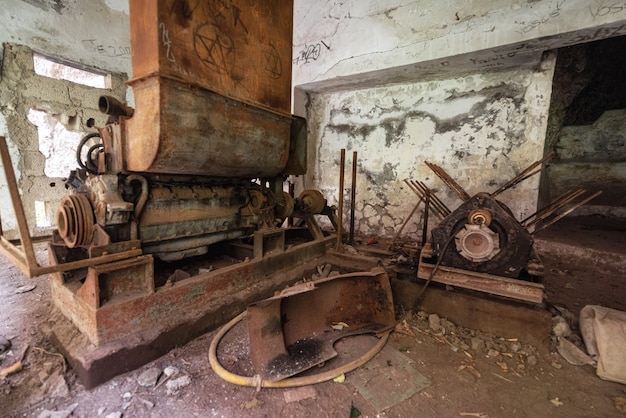 Anciennes machines-outils industrielles abandonnées et équipement en métal rouillé dans une usine désaffectée.